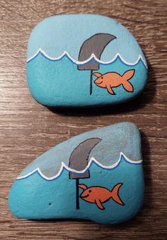 two rocks with fish and umbrella painted on them