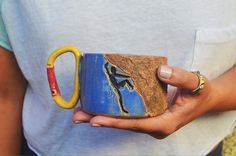 a woman holding a coffee mug with a painting on the outside and inside, in her hands