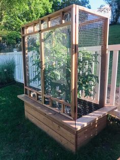 a wooden box with plants growing in it on the grass next to a white fence