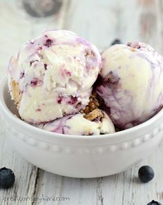 two scoops of ice cream in a bowl with blueberries