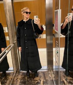 a woman taking a selfie in front of an elevator door with her cell phone