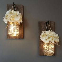 two mason jar wall sconces with flowers on them are hanging from the wall