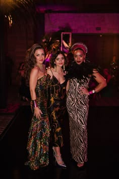 three women standing next to each other at a party