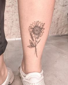 a woman's foot with a small sunflower tattoo on her left calf and the lower leg