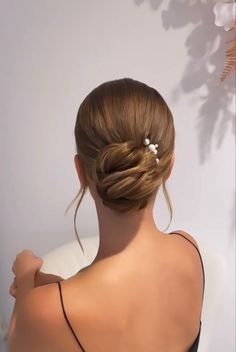 a woman with her back to the camera, wearing a black top and white flowers in her hair