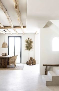 an open living room with white walls and wooden beams on the ceiling, along with potted palm tree