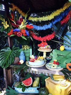 a table topped with lots of fruit and veggies next to a wall covered in streamers