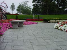 a stone bench sitting in the middle of a garden filled with pink and white flowers