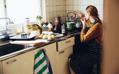 a woman is sitting at the kitchen sink