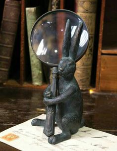 a statue of a rabbit holding a magnifying glass on top of a piece of paper