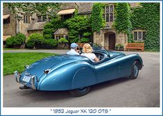 an old fashioned blue sports car parked in front of a house