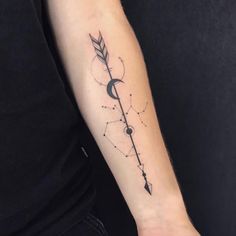 a person with a black and white tattoo on their arm holding an arrow in the shape of a moon