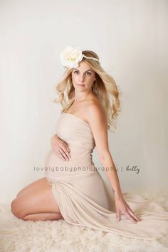 a beautiful blonde woman in a beige dress posing for a photo with her hands on her hips