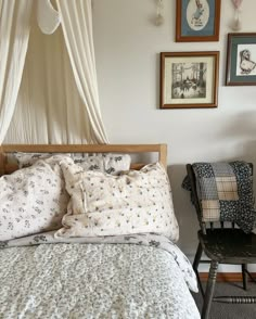 a bed sitting in a bedroom next to a chair and pictures on the wall above it