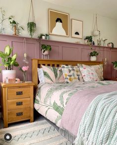 a bed sitting in a bedroom next to a wooden dresser and potted plants on top of it