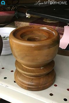 two wooden vases sitting on top of a white shelf next to plates and bowls