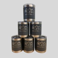 six black and gold canisters stacked on top of each other with mountains in the background