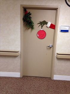 a door decorated for christmas with a santa hat and handprinted ornament