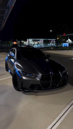 a black sports car is parked in the parking lot at night with its lights on