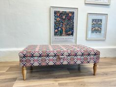 a bench sitting on top of a hard wood floor next to pictures and framed artwork