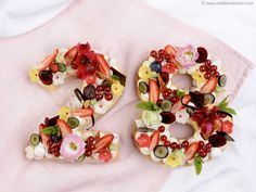 the numbers are made out of fruit and flowers on top of a pink cloth covered tablecloth