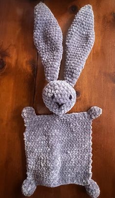 a crocheted stuffed animal sitting on top of a wooden floor next to a piece of wood