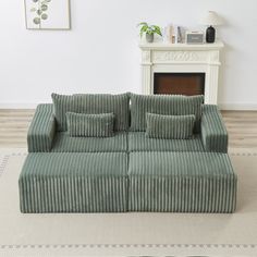 a green couch sitting on top of a rug in front of a white fire place