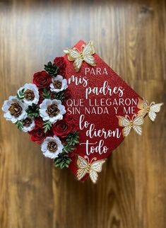 a graduation cap decorated with flowers on top of a wooden table next to a wall