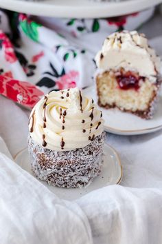 two cupcakes with white frosting and chocolate sprinkles on plates