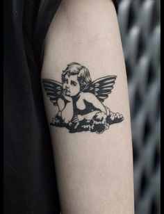 a black and white photo of an angel tattoo on the left upper half of the arm