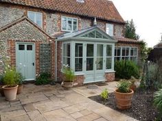 a brick building with several potted plants in front of it and an enclosed patio area