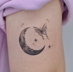 a woman's thigh with a tattoo on it that has a butterfly flying over the moon