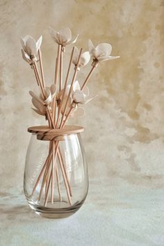 a glass vase filled with white flowers on top of a table next to a wall