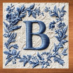 the letter b is made out of blue thread and surrounded by leaves on a white background