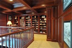 a large library with wooden bookshelves and stairs leading up to the second floor