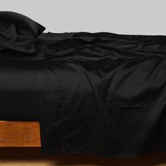 a bed with black sheets and pillows on it