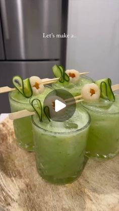 three glasses filled with green liquid and garnished with cucumber on sticks