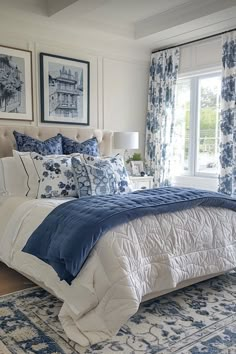 a bed with blue and white comforters in a bedroom next to a window filled with curtains