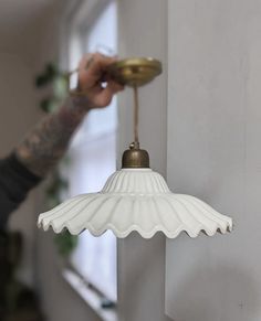 a person holding a light in their hand near a wall with a potted plant on it