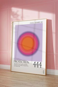 an orange and pink poster is on the floor in front of a pink wall with a white frame