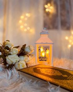 a small white lantern sitting on top of a table next to a bouquet of flowers