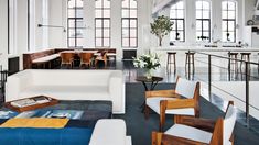 a living room filled with lots of white furniture and tall windowed windows next to each other