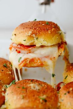 a close up of a plate of food with cheese and sauce on it's buns