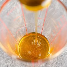 a blender filled with yellow liquid on top of a white countertop next to an orange measuring cup