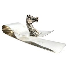 a silver horse head on top of a piece of metal with a long blade in the middle