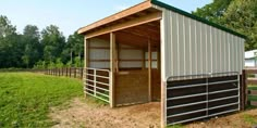 a horse barn with the doors open in a field