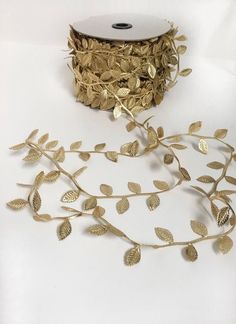 a roll of gold foiled paper with leaves on it next to a spool of tape