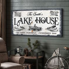 a lake house sign hanging on the side of a wall next to a chair and table