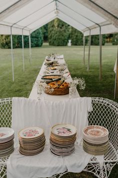 a table topped with lots of plates under a tent