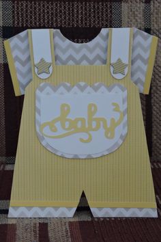 a paper cut out of a baby's yellow outfit with the word baby on it